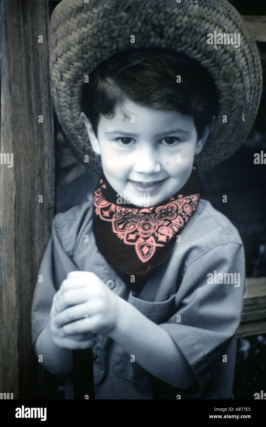 A brown haired toddler dressed in a handkerchief around neck straw