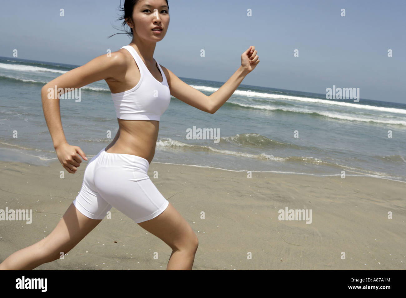 A young woman is running on a beach. Stock Photo