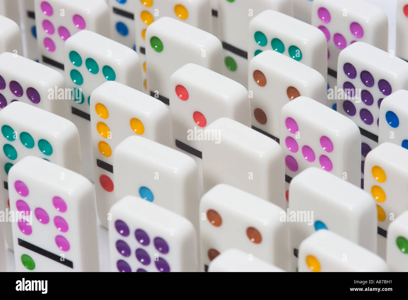 Uniform rows of white dominoes with brightly colored dots standing on end Stock Photo