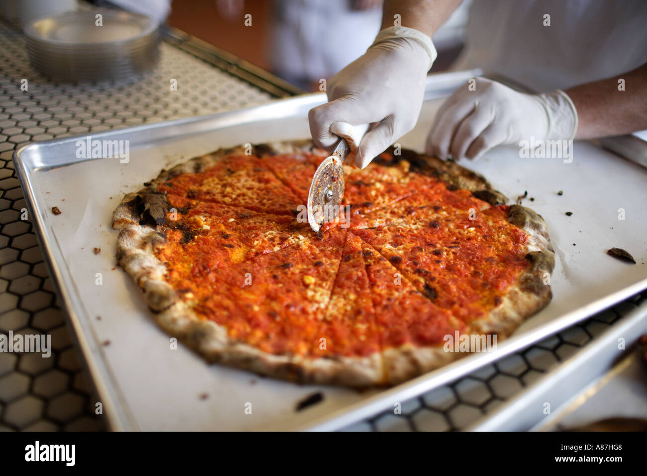 Pizza thin crust variety Brick Oven being cut by pizza makers hands