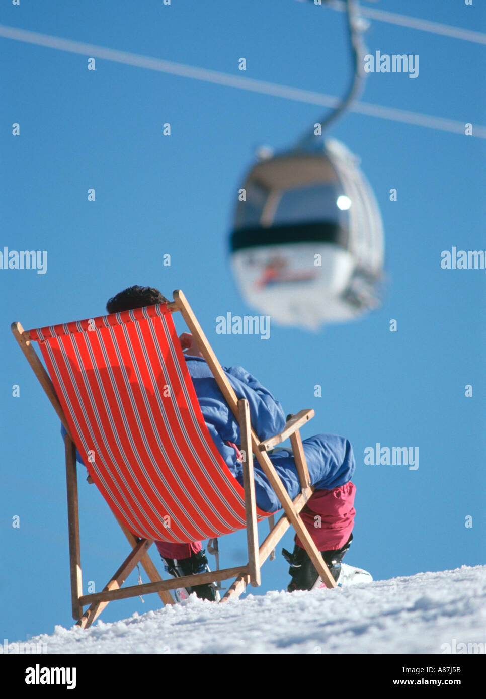 Skier relaxing in a deckchair on the ski slopes with a gondola behind,  Alpbach, Tyrol, Austria Stock Photo