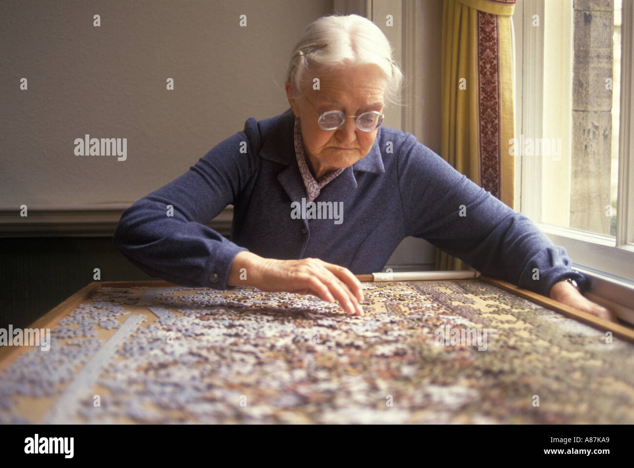 Care Home UK, elderly older lady doing a jigsaw puzzle in her private old people retirement home. Hampshire England 1990s UK HOMER SYKES Stock Photo