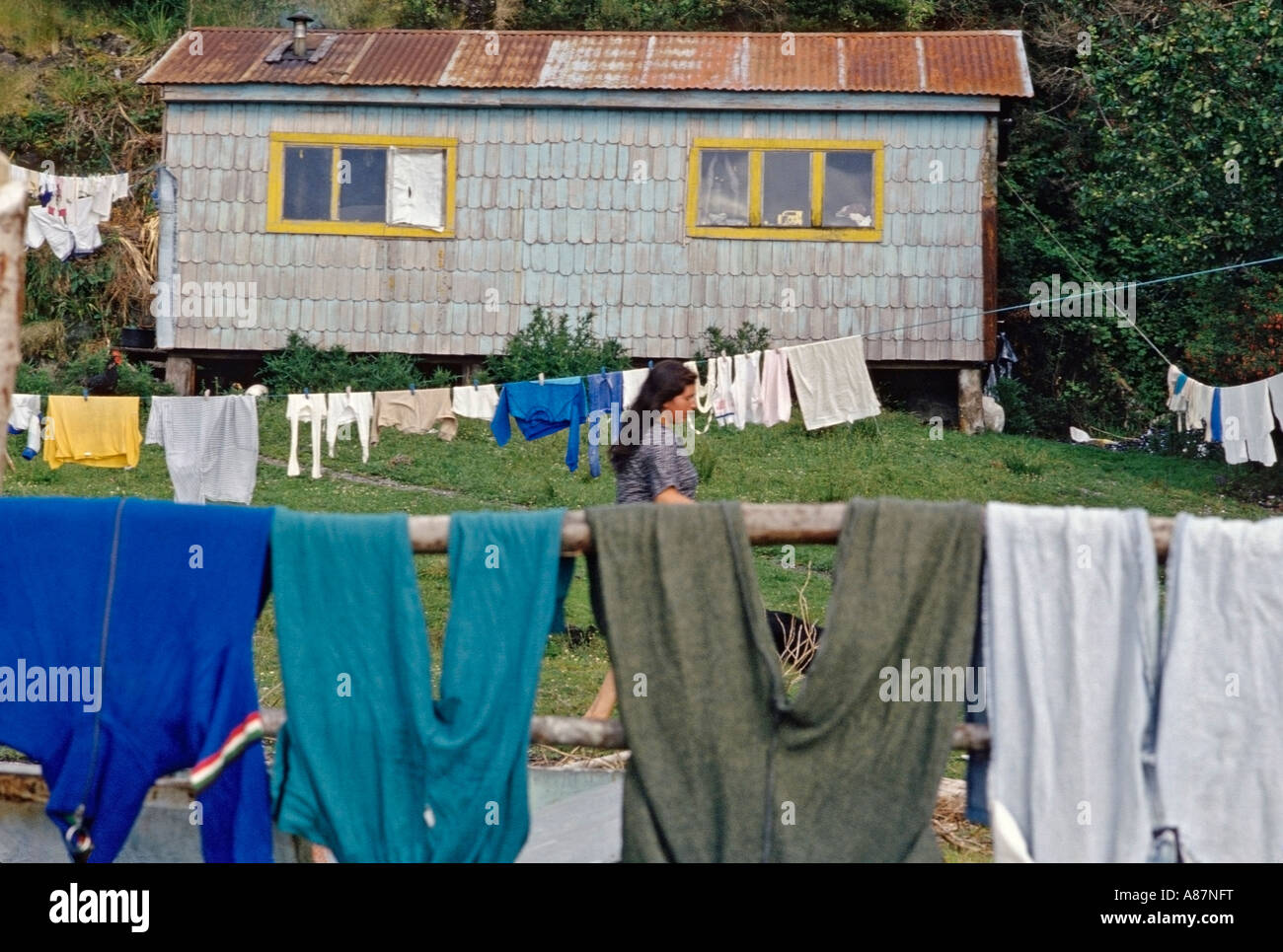 Clothes hanging in the yard of a typical home in La Arena Patagonia Chile with a Chilean woman walking through yard Stock Photo