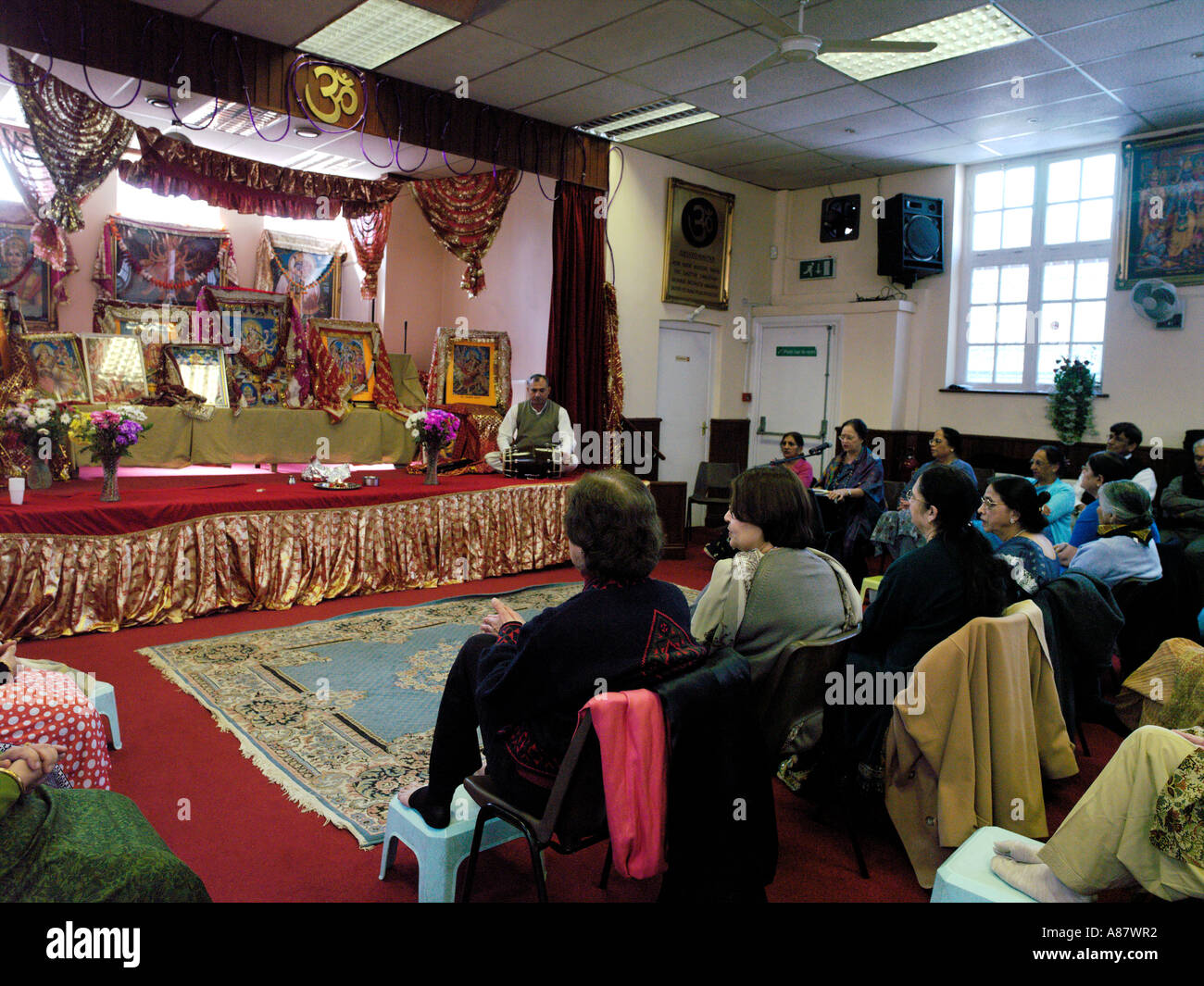 Old Folks Club Meeting and Priest with Tabla on Stage in Hindu Centre Wimbledon London England Stock Photo