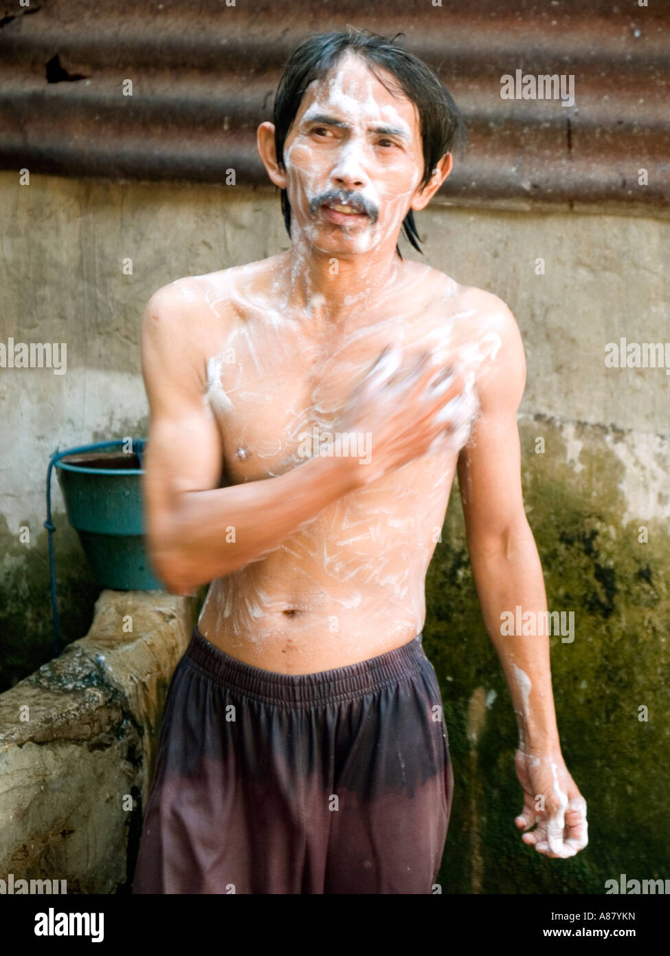 Local man showers in a public bathing area in a slum area of Surabaya