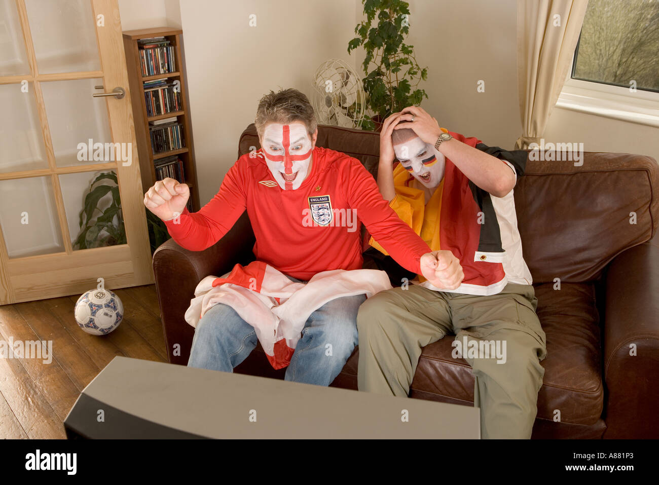Model released. England and German football fans watching match on TV as England wins and Germany looses. Stock Photo