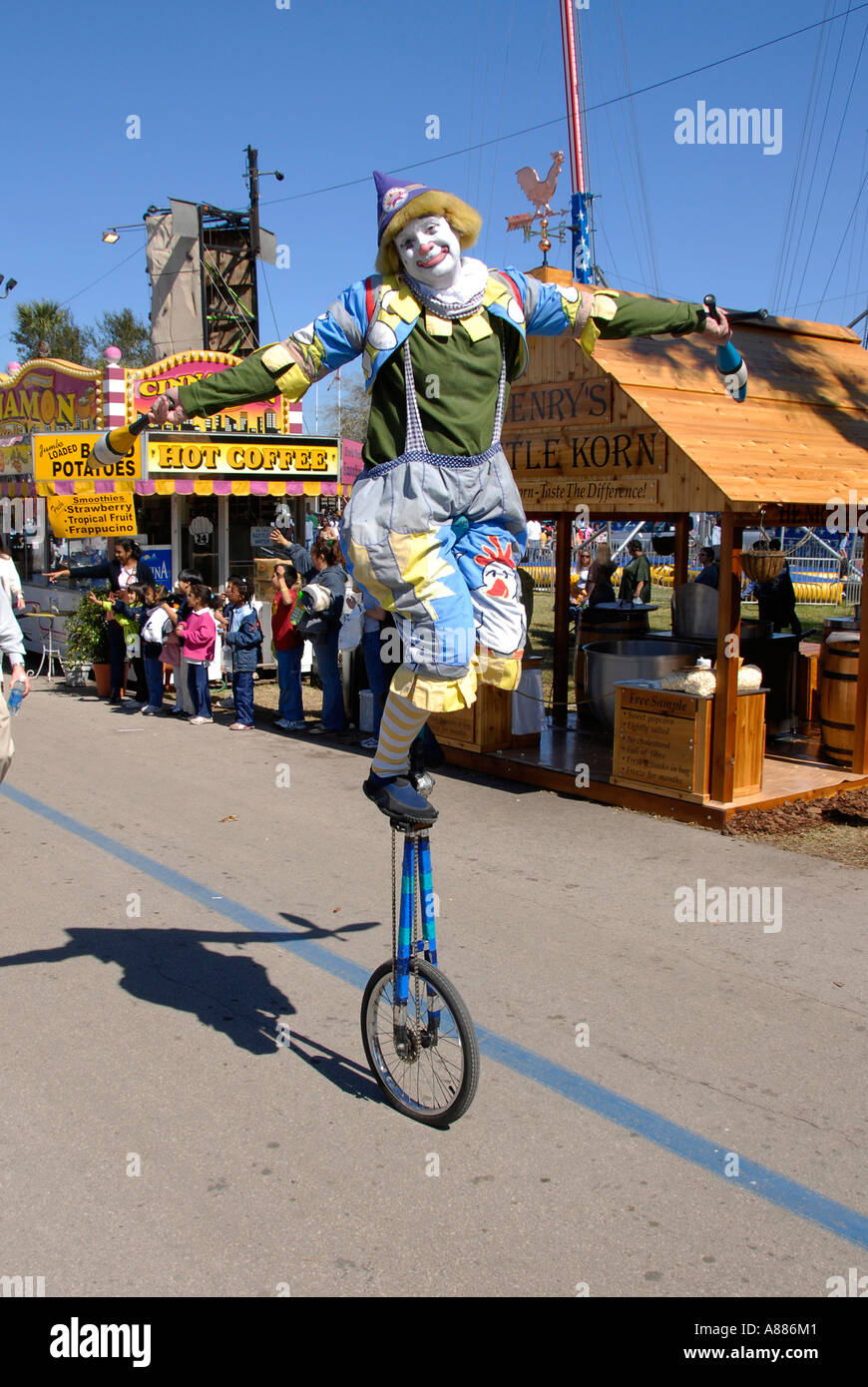 Clown riding on a unicycle participates in a parade at the Florida State Fair in Tampa Florida FL Stock Photo