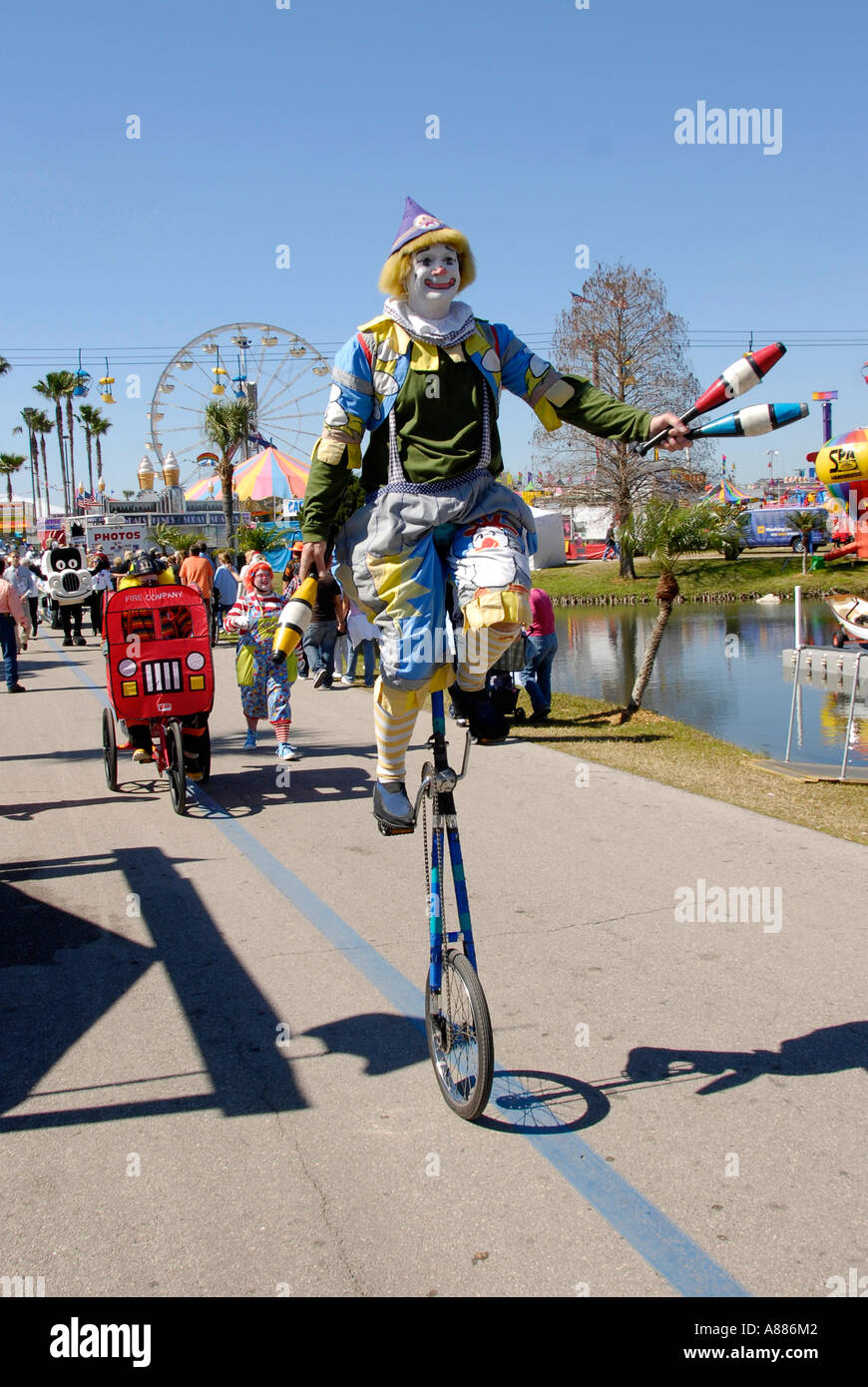 Clown riding on a unicycle participates in a parade at the Florida State Fair in Tampa Florida FL Stock Photo