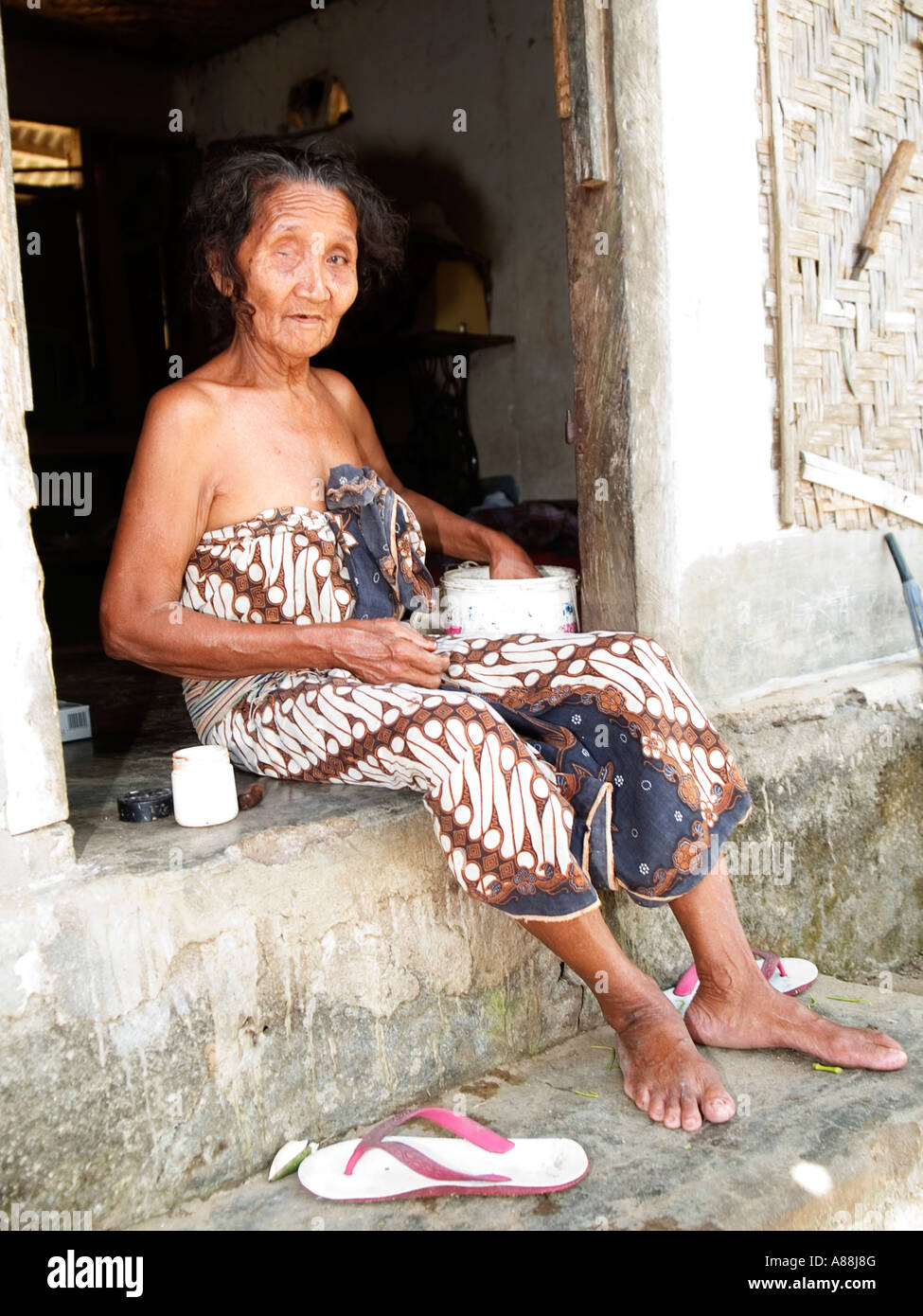 Elderly local woman sitting in the doorway of her traditional rural