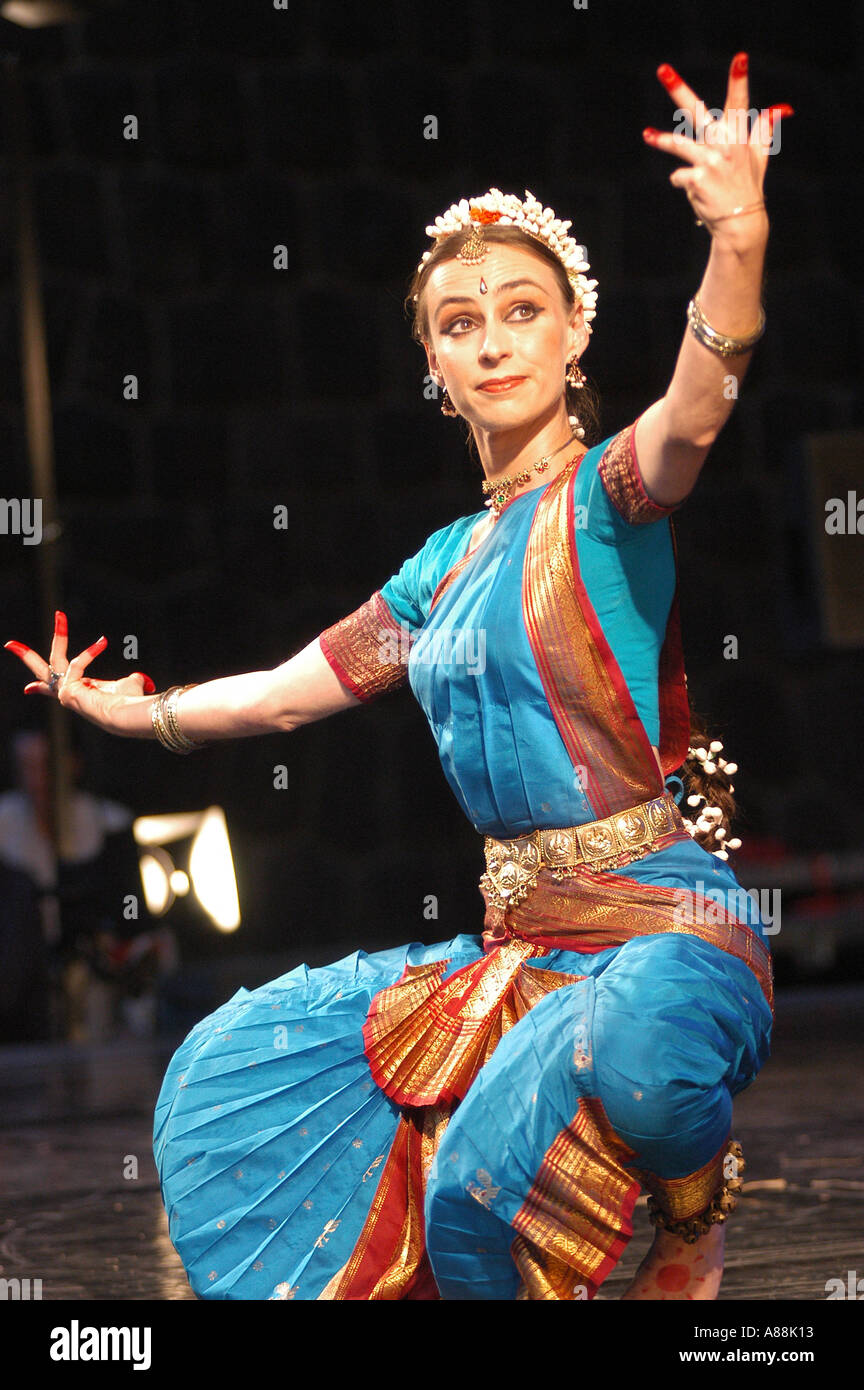 princess polly baby blue dress European female dancer performing traditional Indian dance in a vibrant blue  and gold costume on a dark stage Stock Photo