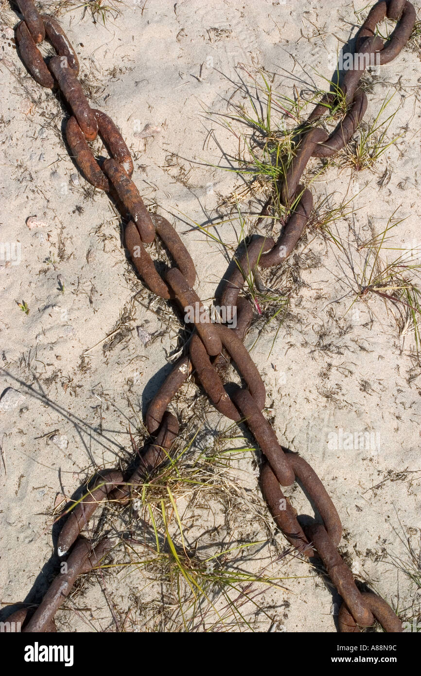 Two half buried rusty iron chains forming character X on sand Stock ...