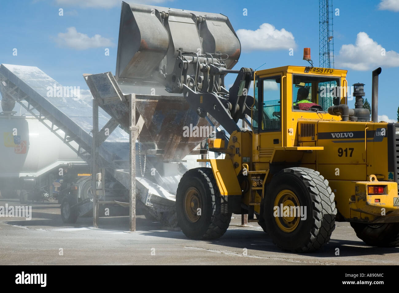 Volvo wheeled loader using a hopper and conveyor belt to load powdered material into a bulk