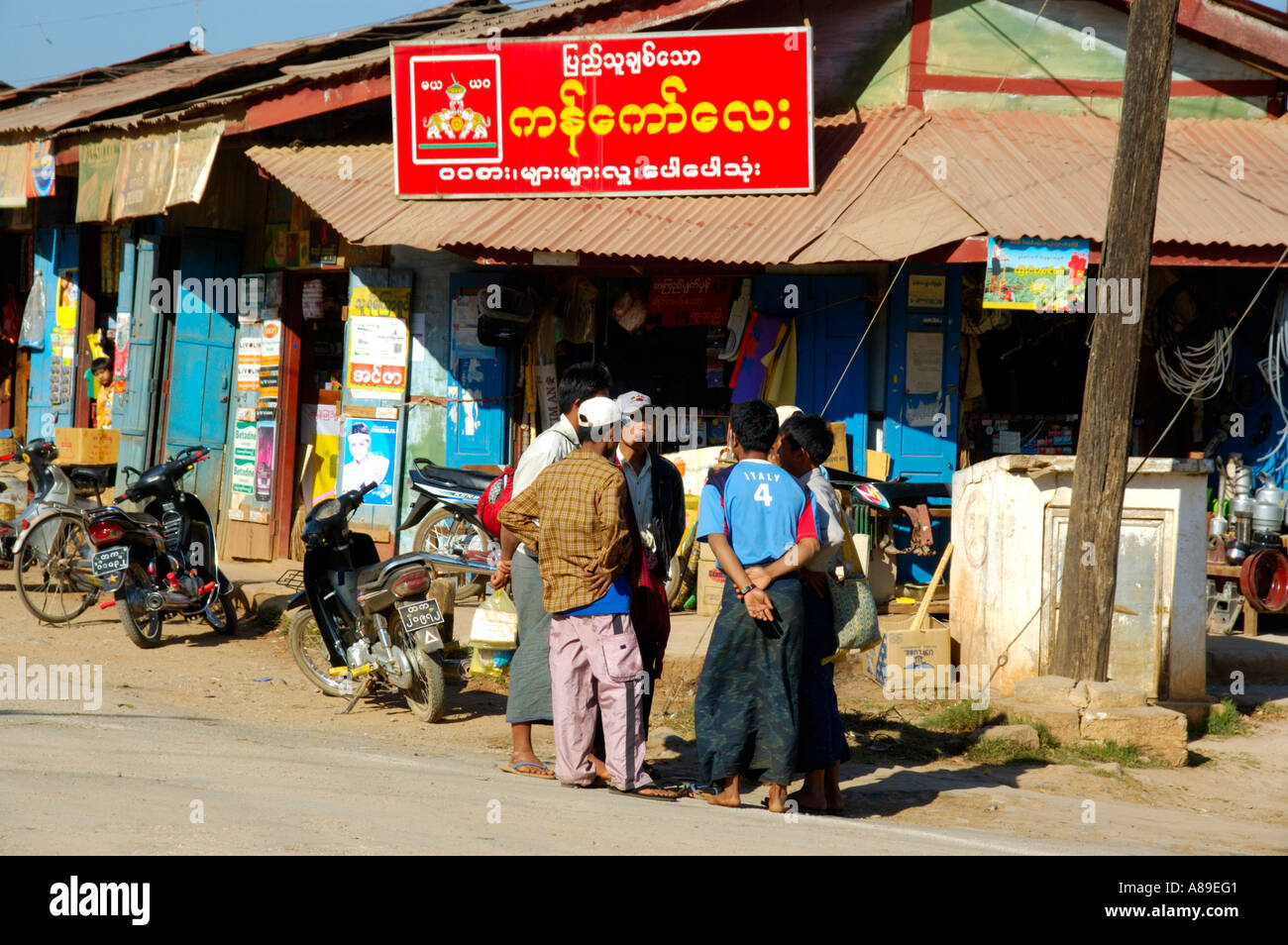 Group of men standing at a shop with sign in Burmese script Pindaya Shan State Burma Stock Photo