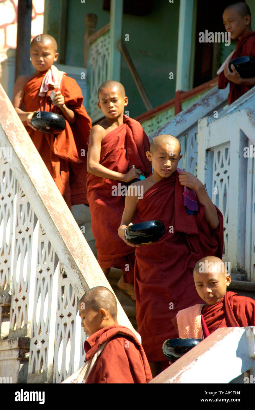 Novices in red robes walk down stairs in a row Maing Thauk Forest Monastery Shan State Burma Stock Photo