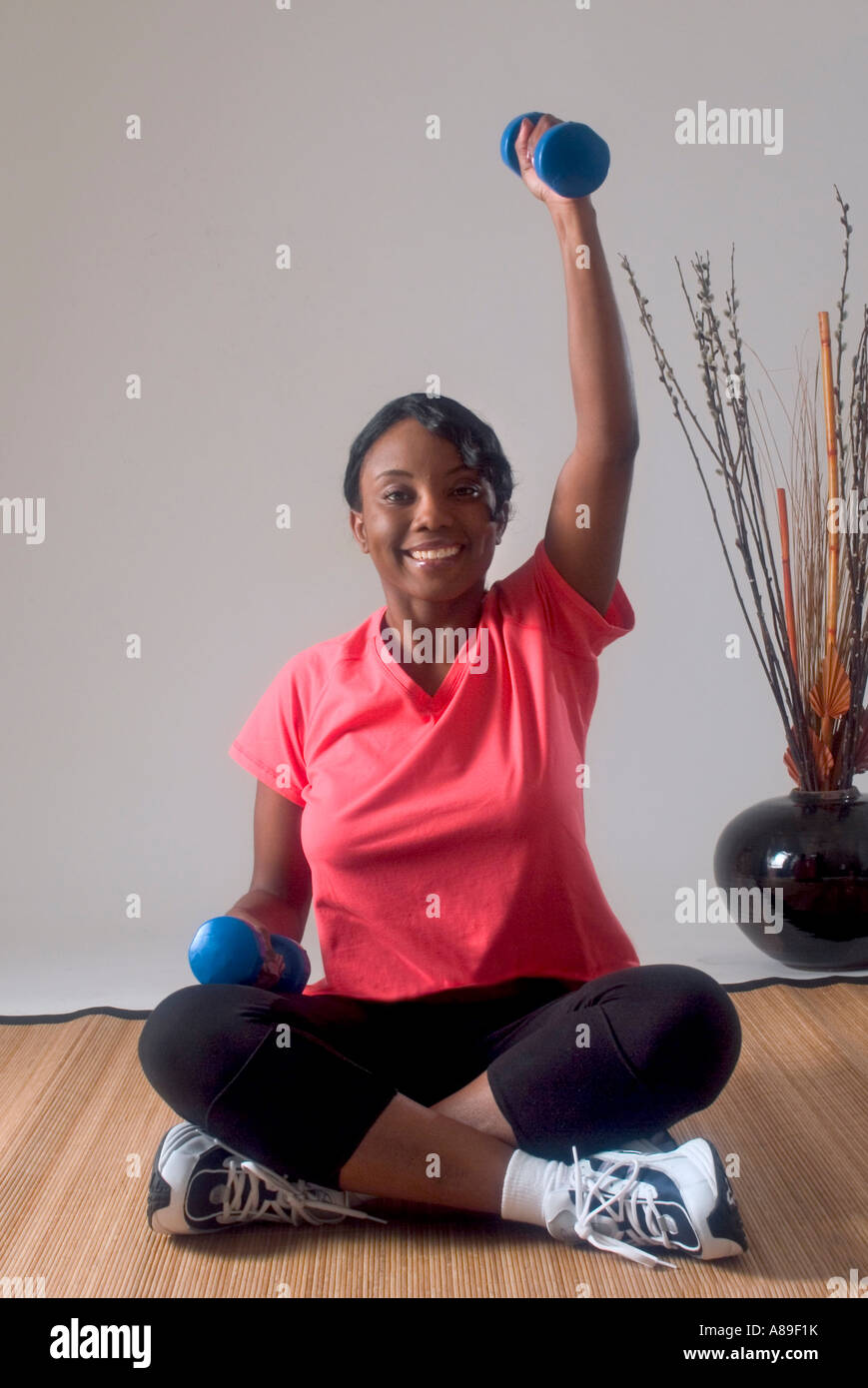 View of a young pretty ethnic black woman lifting dumbbells Stock Photo