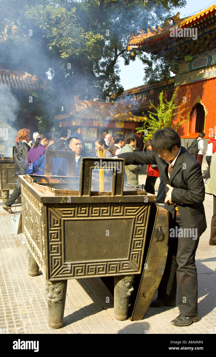 CHINA BEIJING Chinese Buddhists including a young businessman in a suit burn incense and pray Stock Photo
