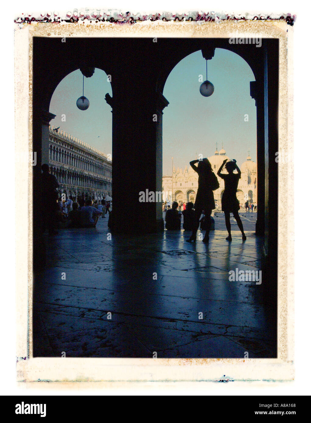 Two figures silhouetted in archway in front of Basilica San Marco Venice Italy Stock Photo