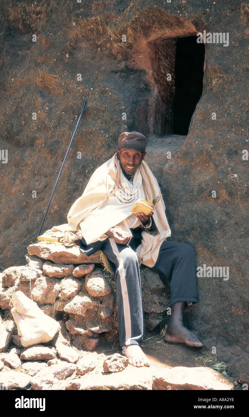 Monk praying at the entrance to his cave just outside a rock hewn church Lalibela Ethiopia East Africa Stock Photo
