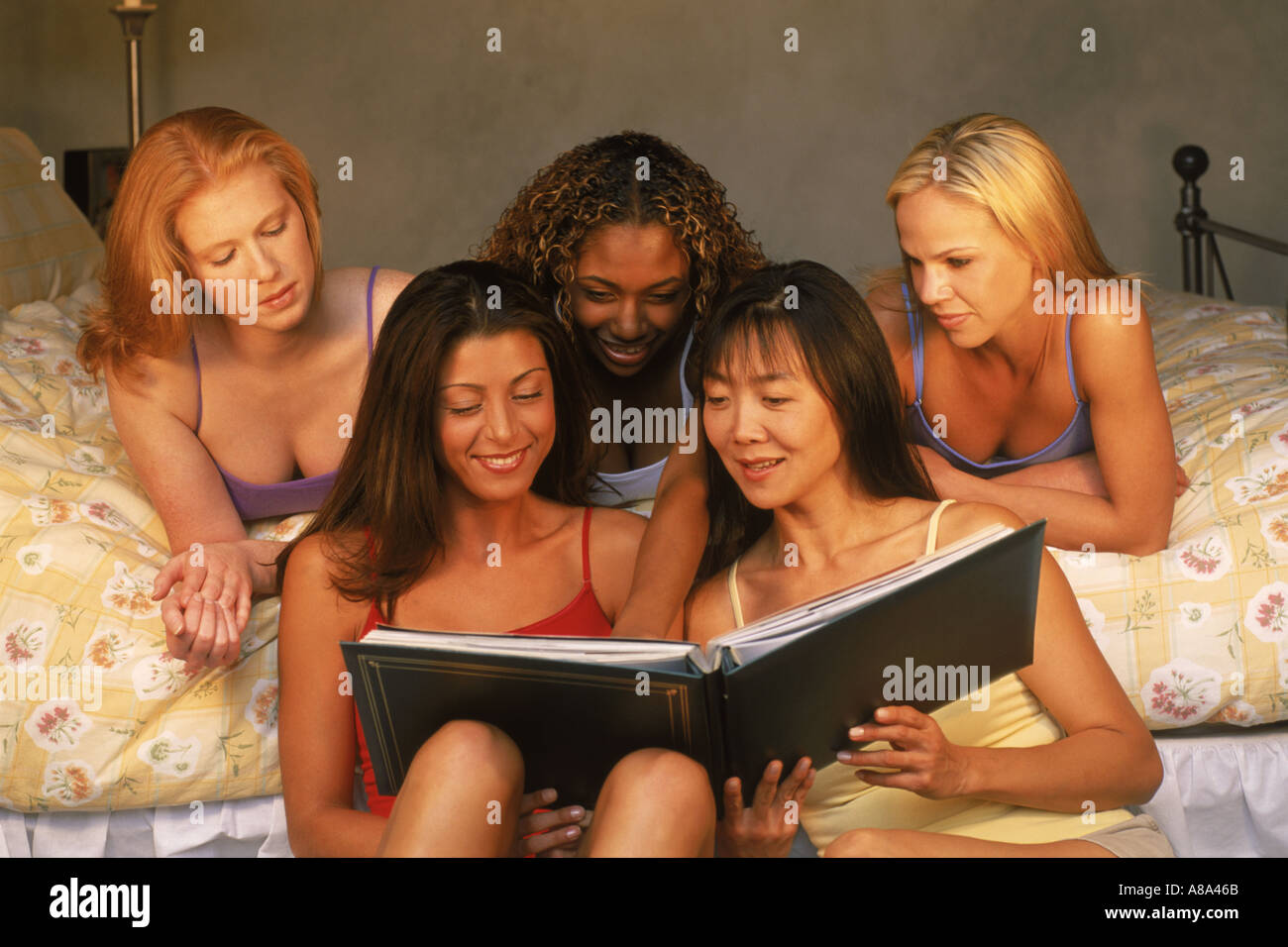 Five friends and four different races sharing photo book in bedroom Stock Photo