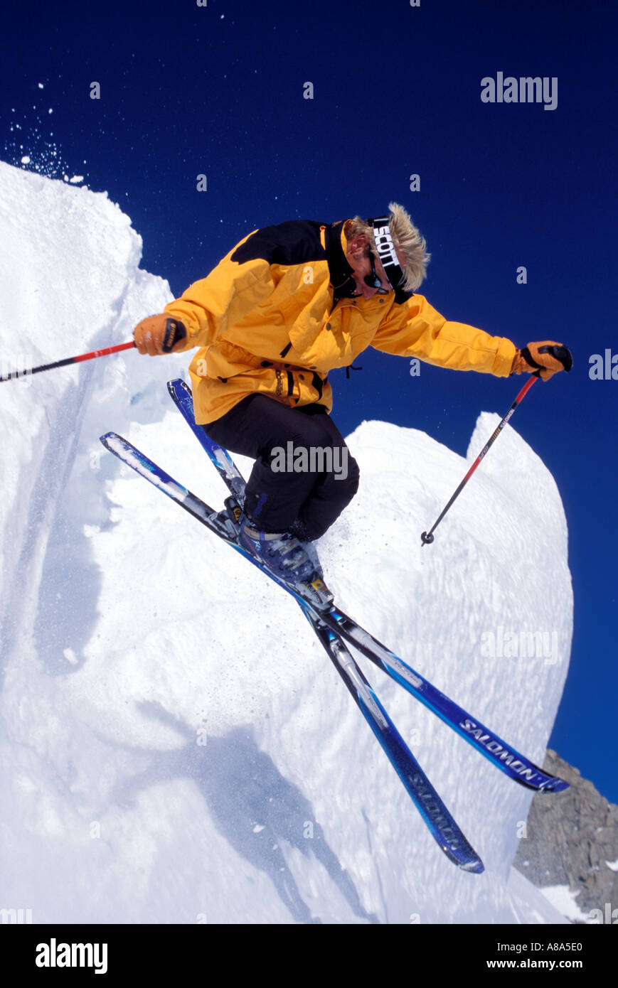 Extreme skier coming off snow ledge at speed  Stock Photo