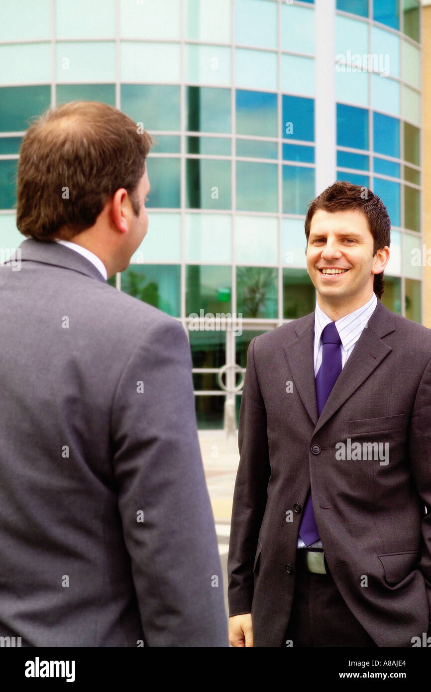 Two men wearing suits, one facing the camera and one with his back to ...