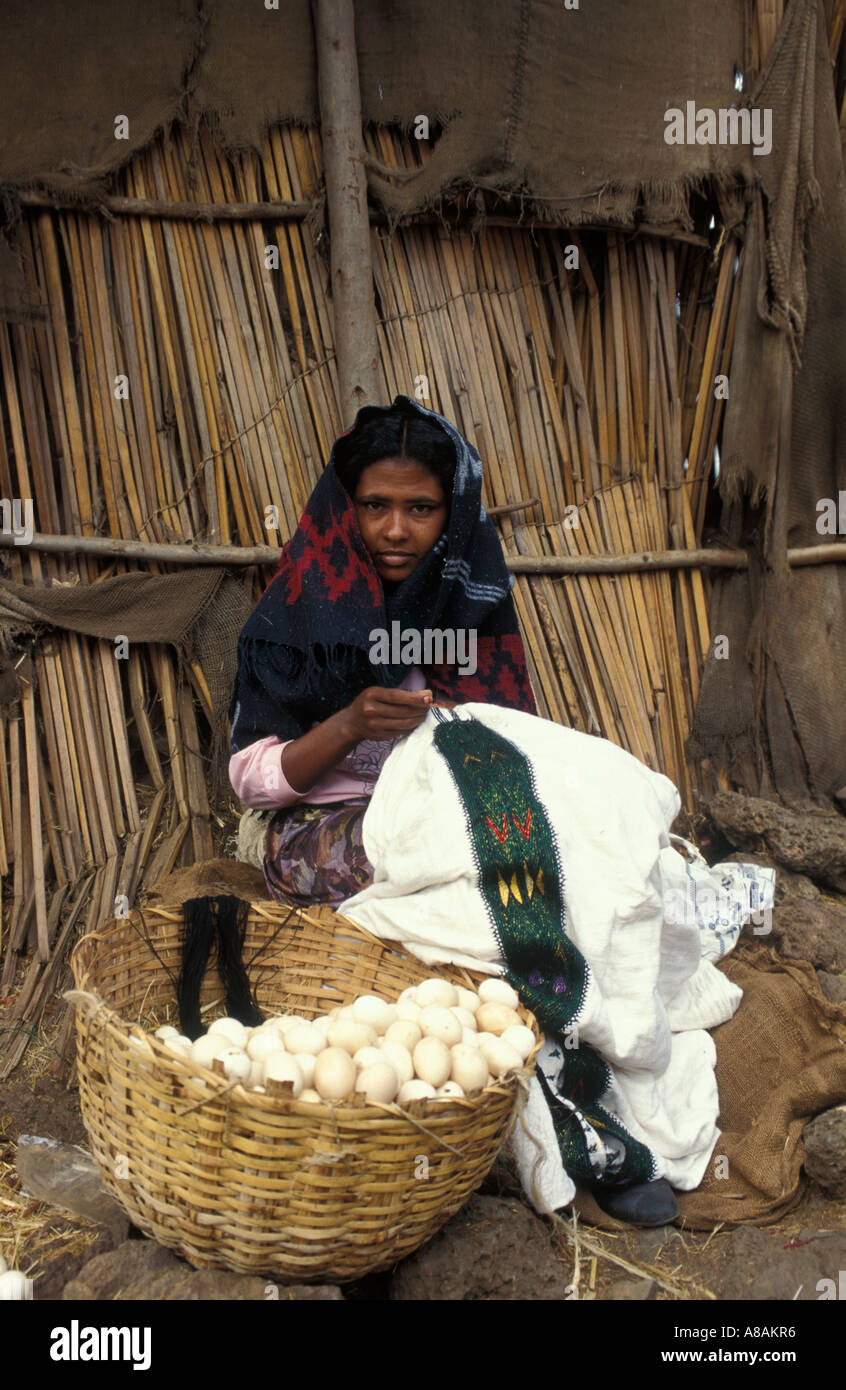 girl embroidering an Ethiopian dress while selling eggs in the Central Market Bahir Dar, Ethiopia Stock Photo