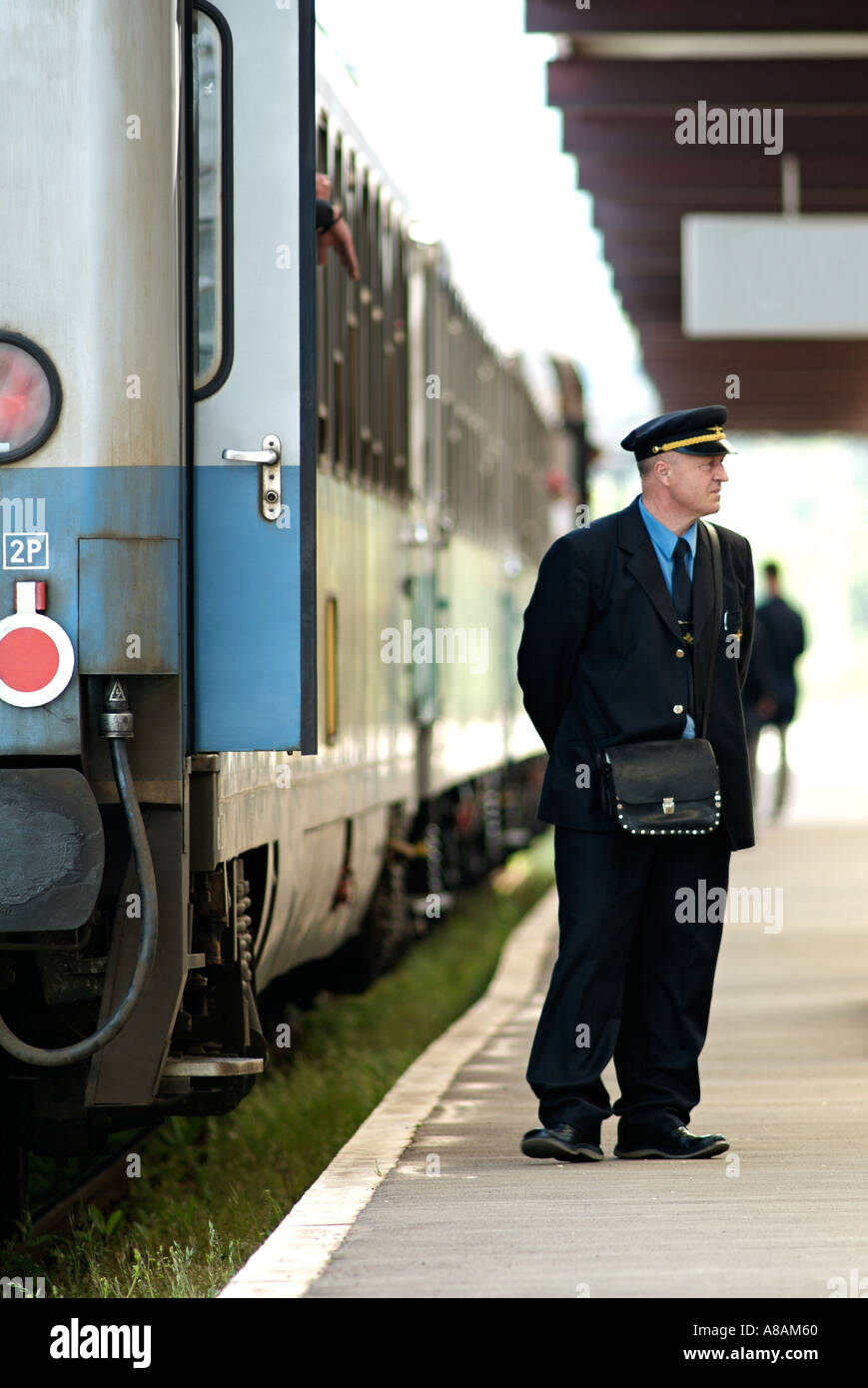 Railway Train Conductor Standing on a Station Platform Next to a Train Carriage. Stock Photo