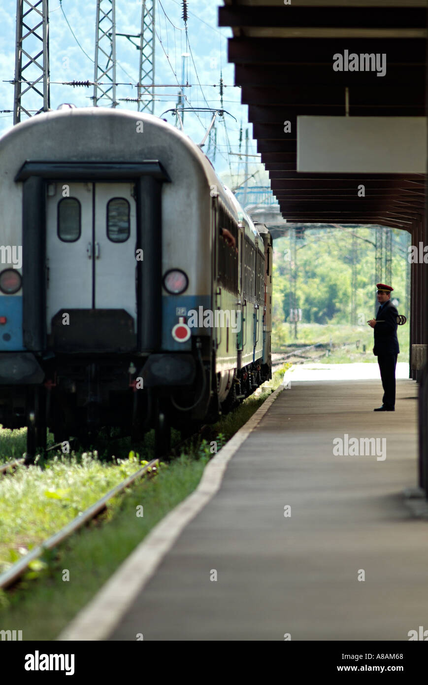 Railway Station Master Standing on the Platform as a Train Departs. Stock Photo