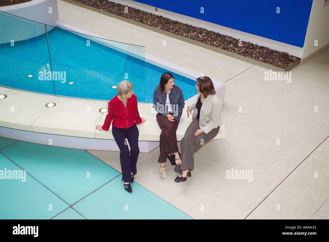 Three ladies enjoying a chat together in the atrium of a a modern city centre block of apartments Stock Photo