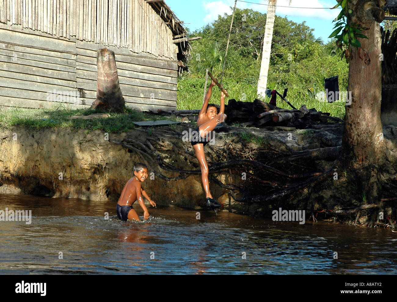 In Venezuela's Orinoco river delta Warao Indian boys play at the river's edge Stock Photo