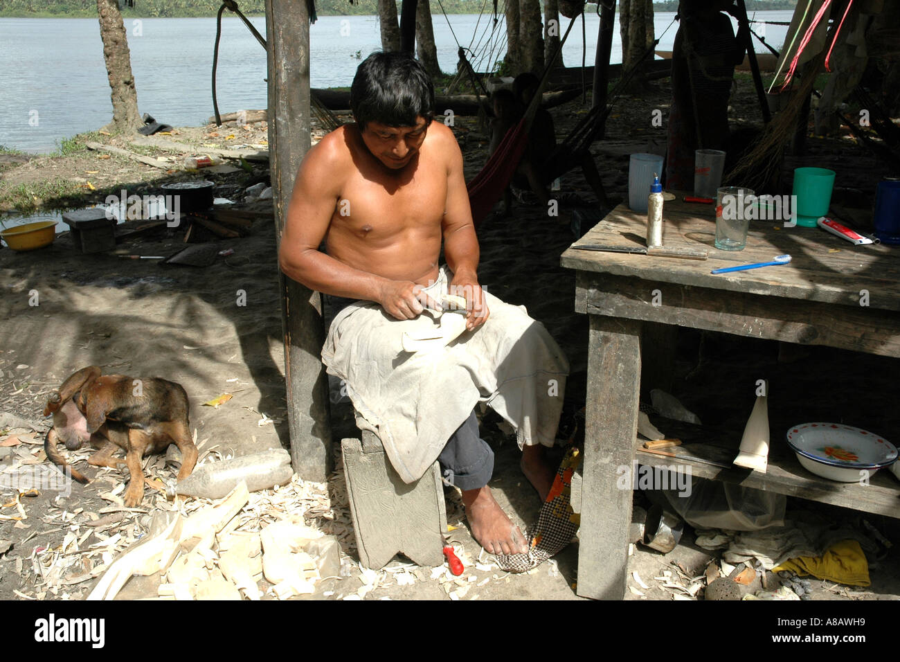 A Warao woodcarver in Venezuela's Orinoco river delta works on a small carving which he aims to sell to tourists Stock Photo