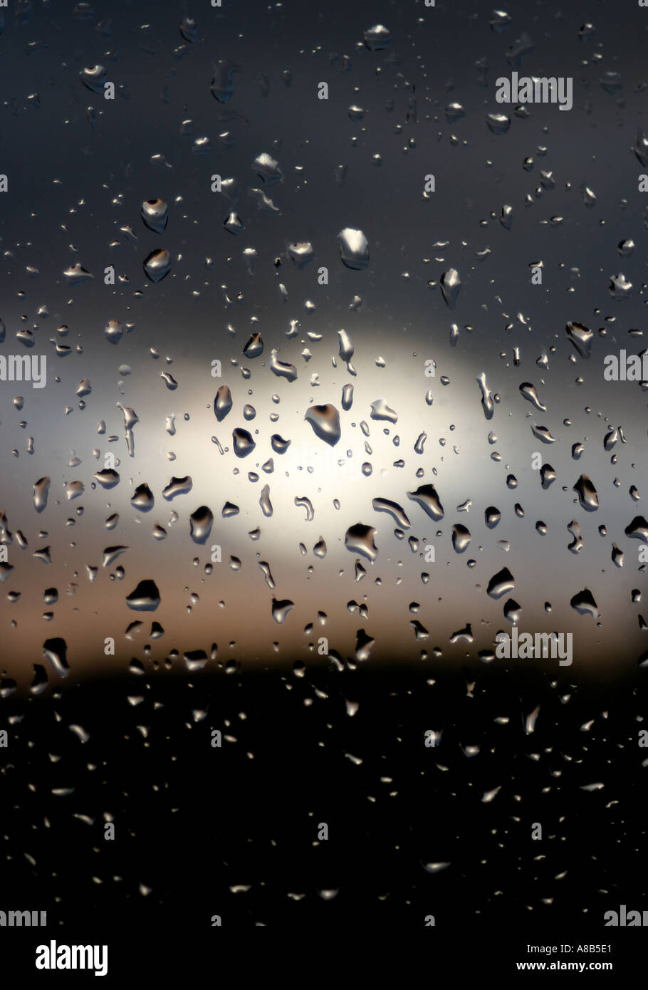 RAIN DROPS ON WINDOW PANE AS SUN SETS Stock Photo