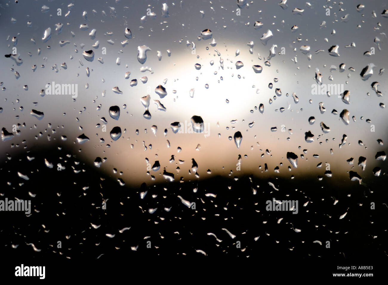 RAIN DROPS ON WINDOW PANE AS SUN SETS Stock Photo