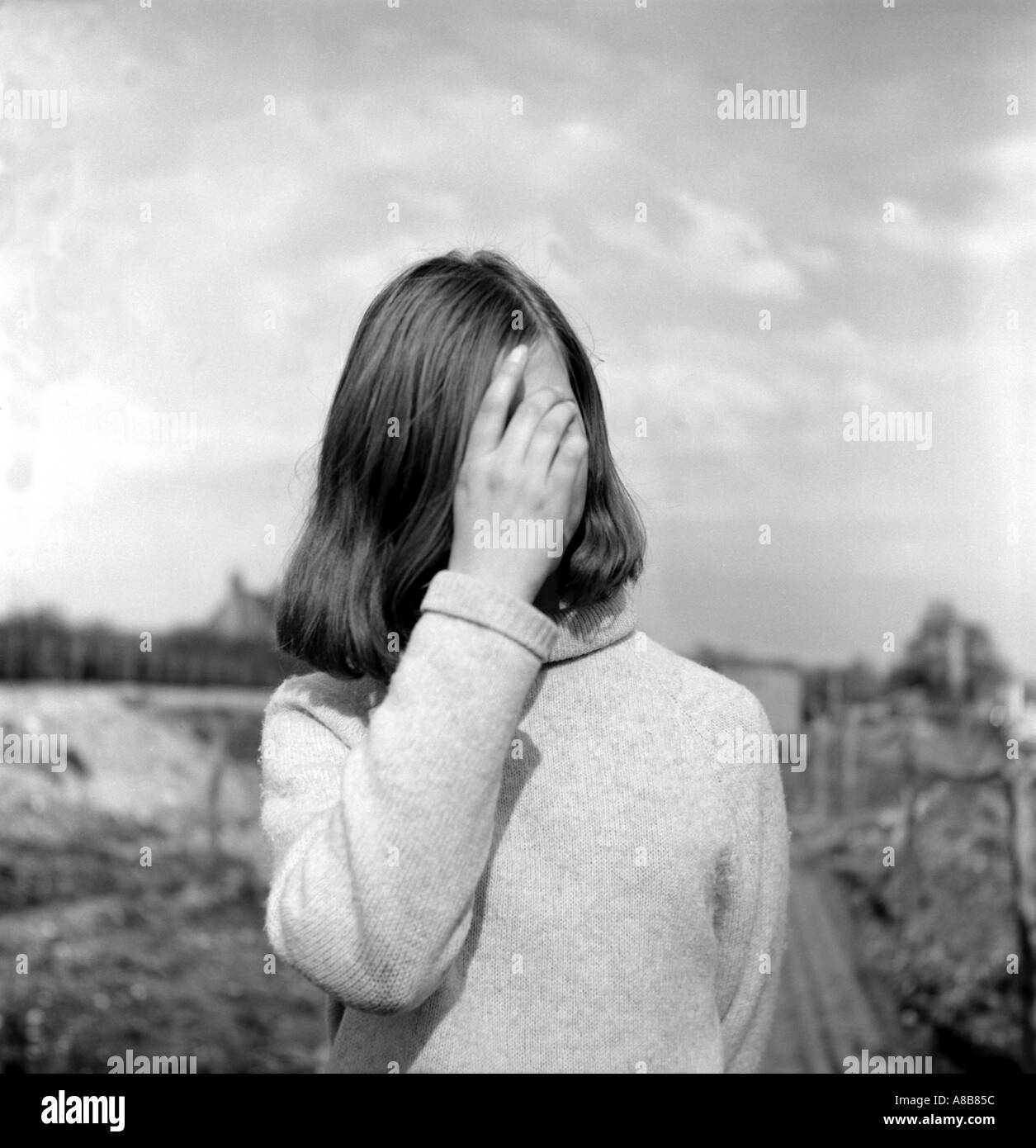 Black and white portrait of a young woman from 1968 hiding her face with her hand Stock Photo