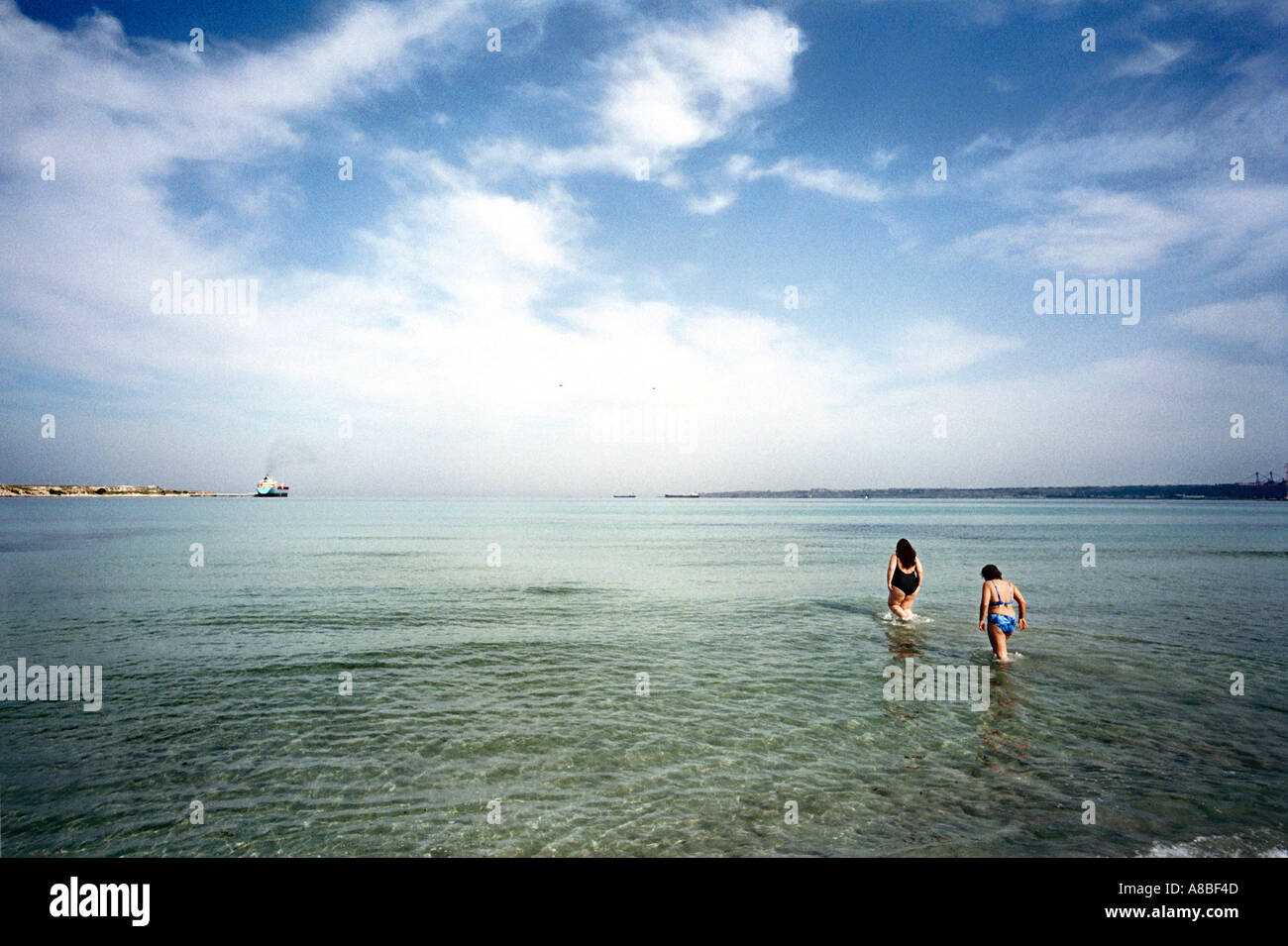 Girls entering the water Priolo Gargallo Sicily Italy Stock Photo