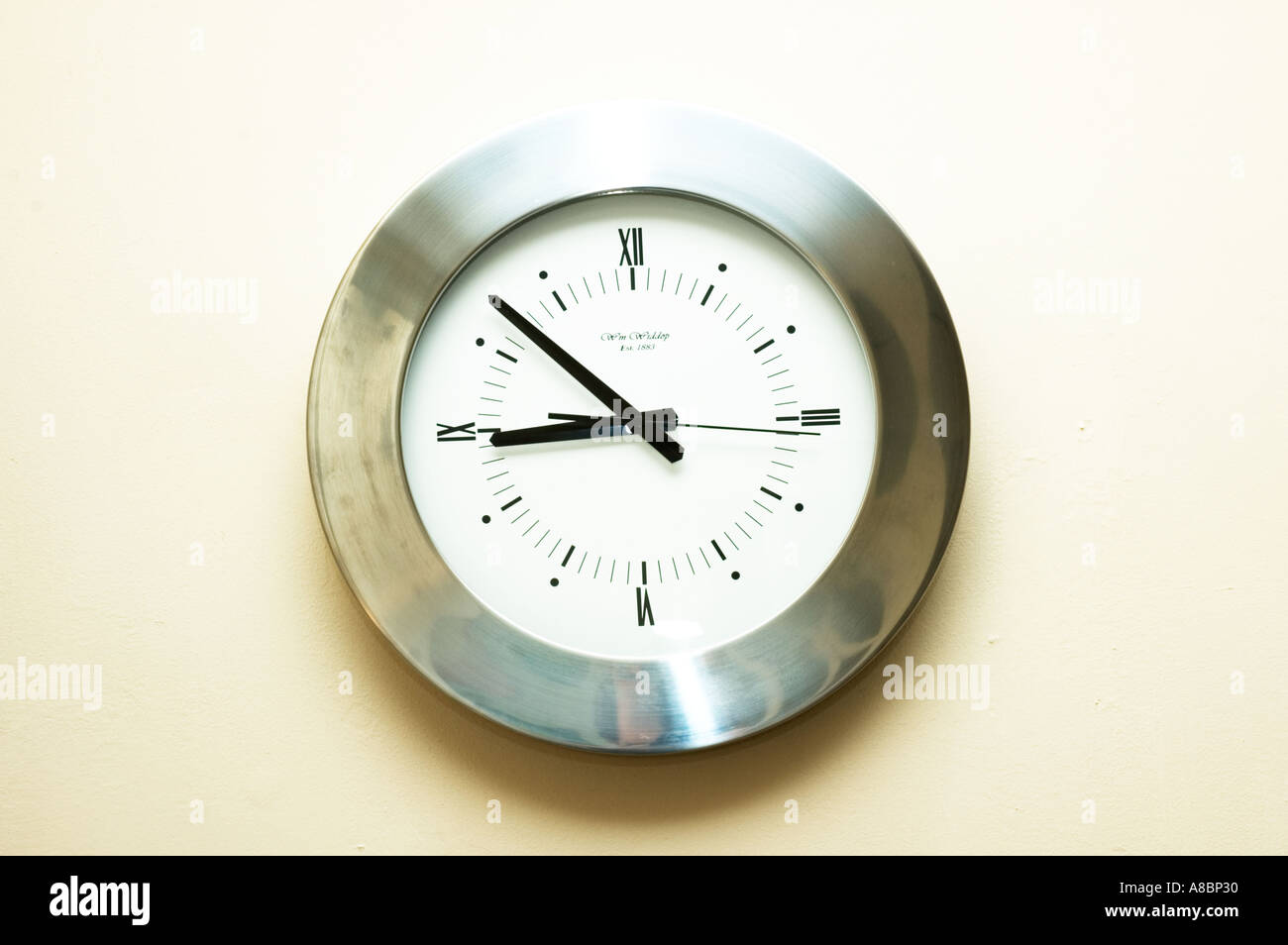 silver analogue clock on the wall with white background Stock Photo - Alamy