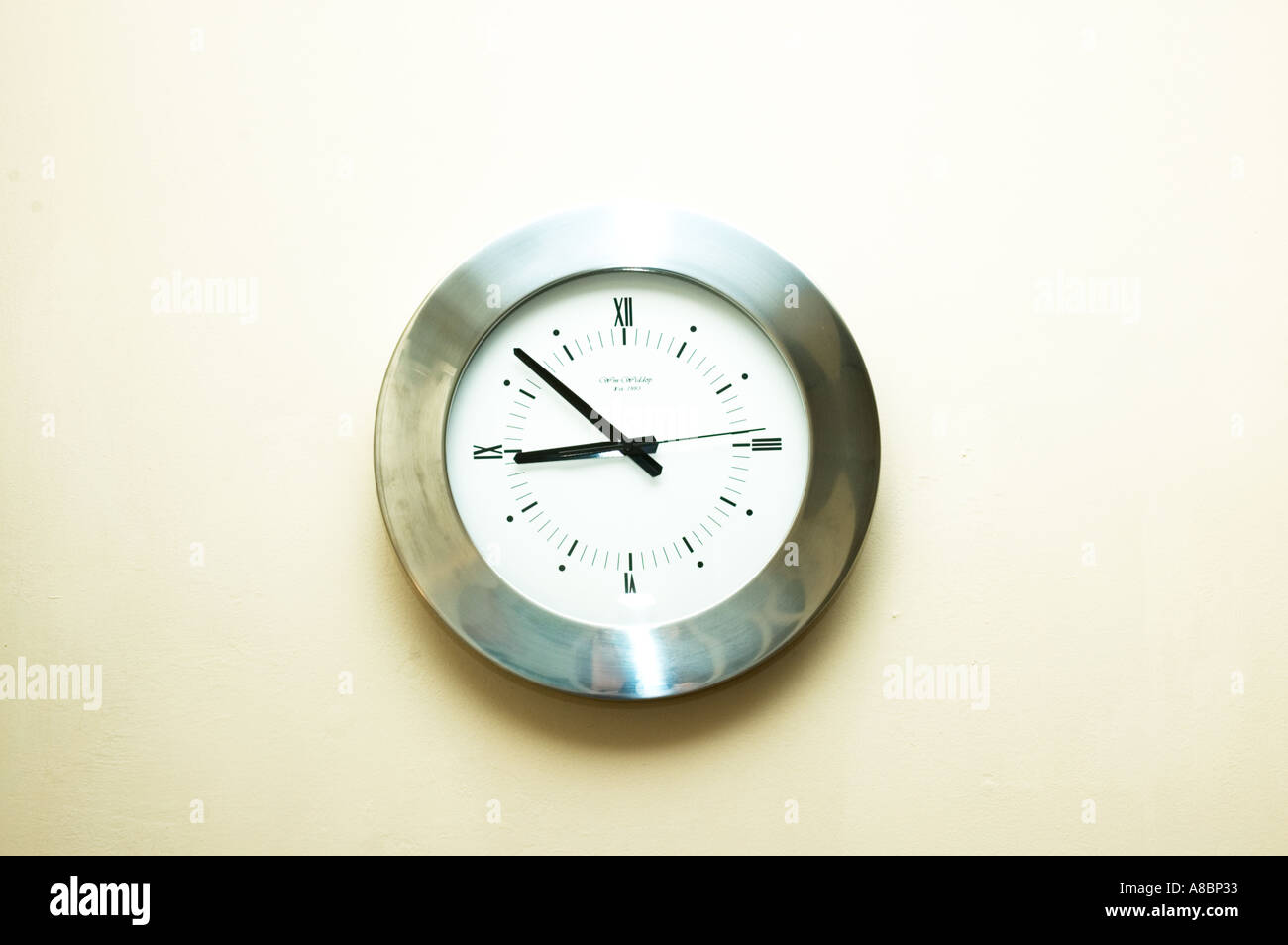 silver analogue clock on the wall with white background Stock Photo - Alamy