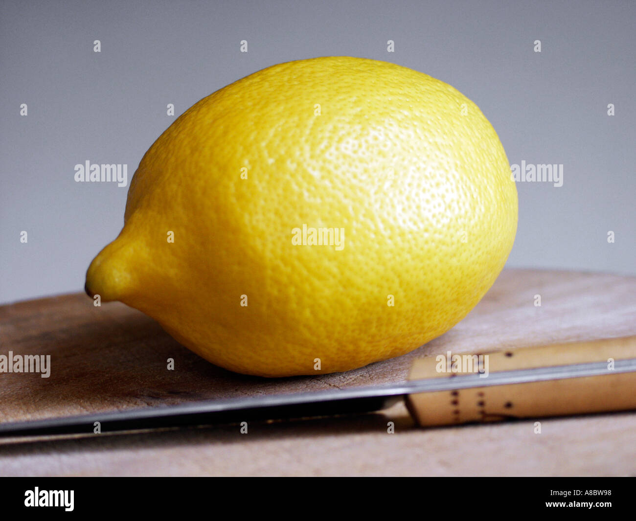Lemon and knife on wooden board Stock Photo