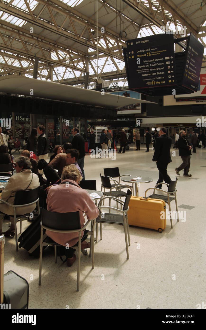 Waterloo railway station concourse people sitting at snack bar tables with possible unattended yellow suitcase Stock Photo