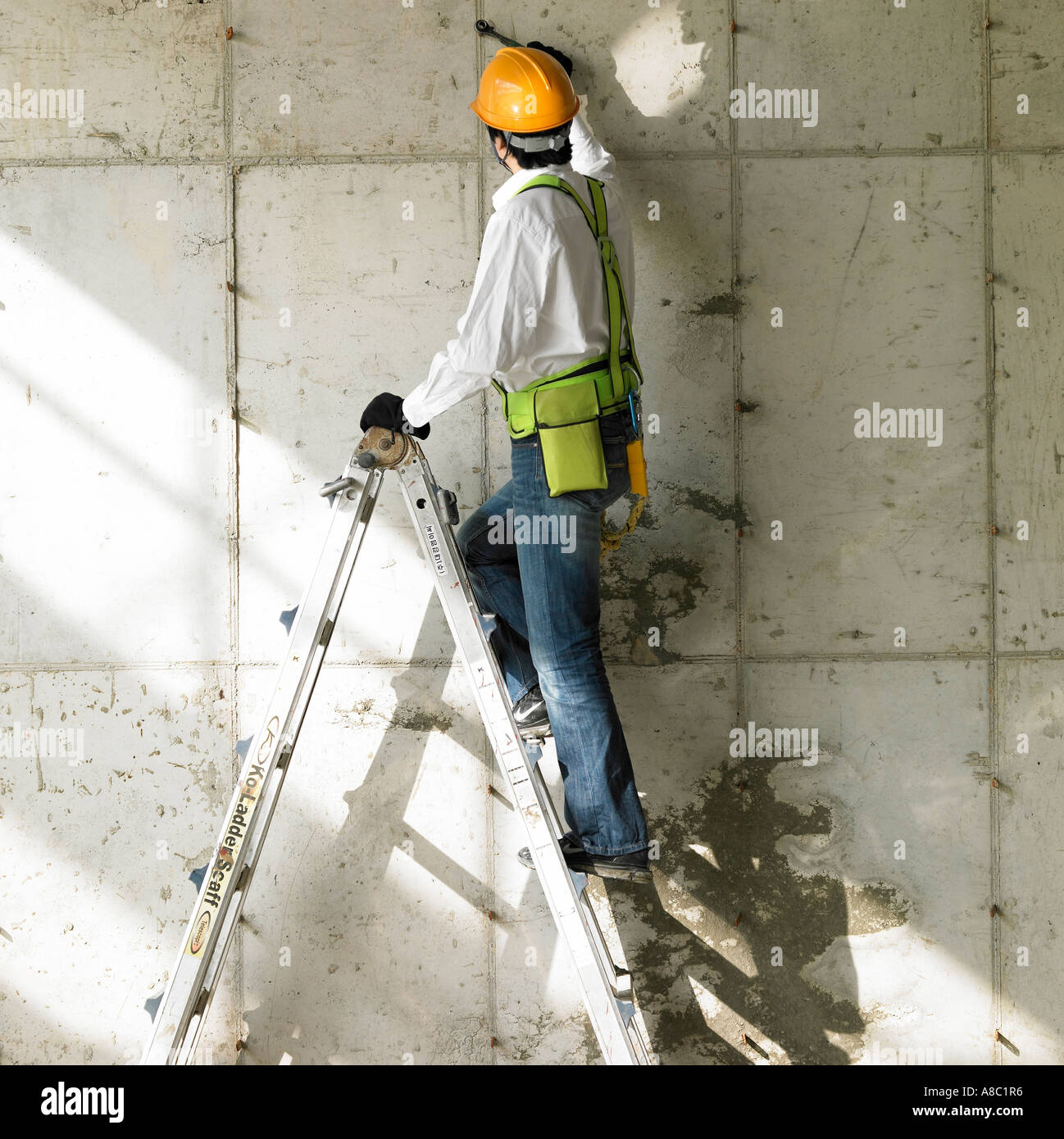 at a construction place a worker working on a ladder Stock Photo