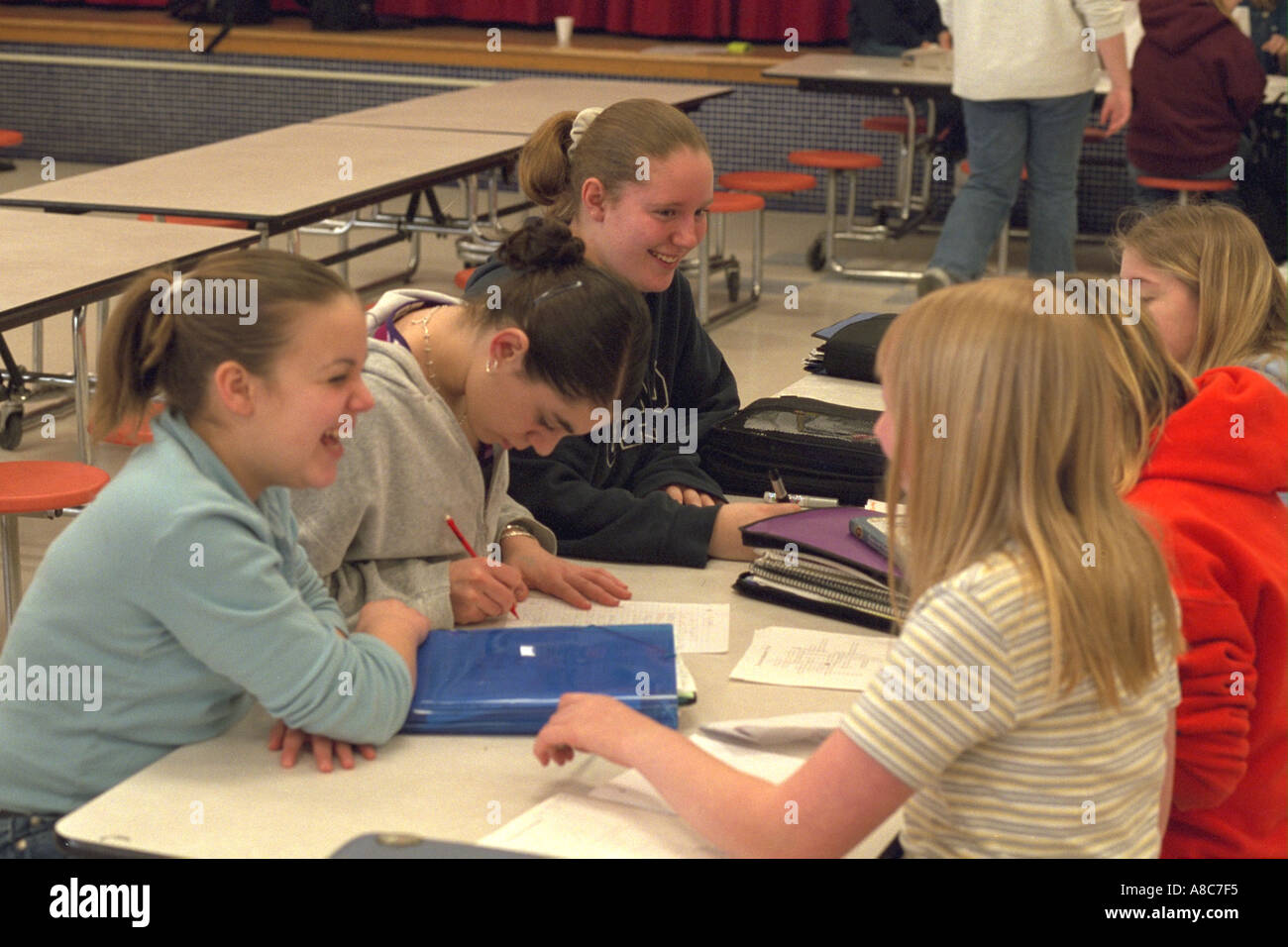 Girls age 14 laughing and talking in school study hall. Golden Valley Minnesota USA Stock Photo