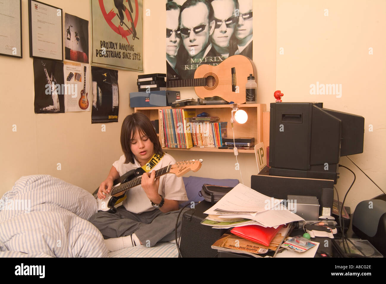 12 Year Old Boy Practising Guitar In His Bedroom Stock Photo