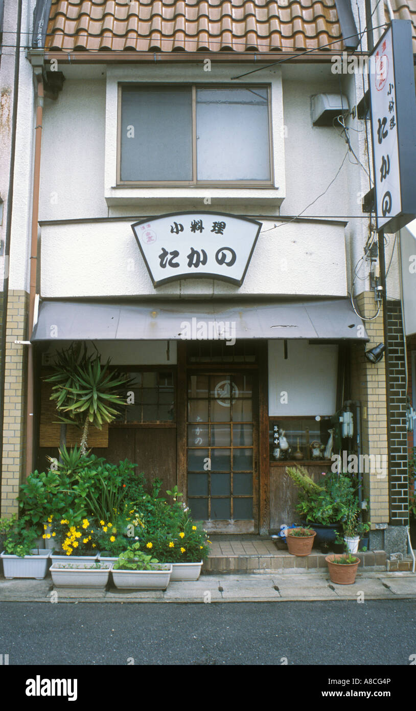 A small Japanese restaurant on Kyushu with plants on the pavement