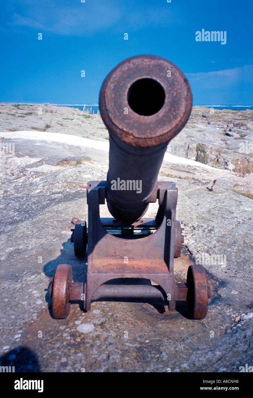 Old wheeled naval cannon on rock by the sea. Stock Photo