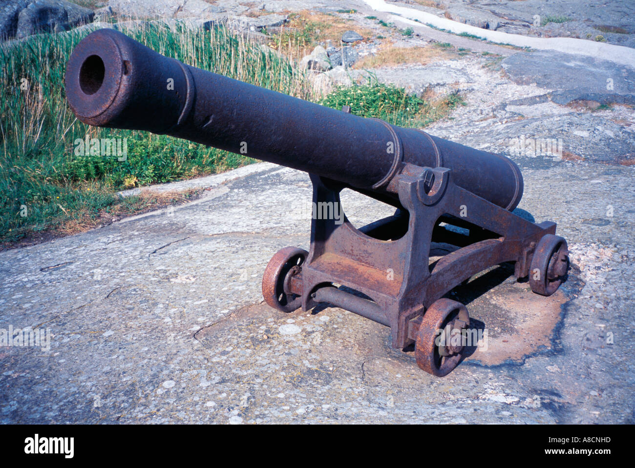 Old wheeled Naval Cannon on rock. Stock Photo