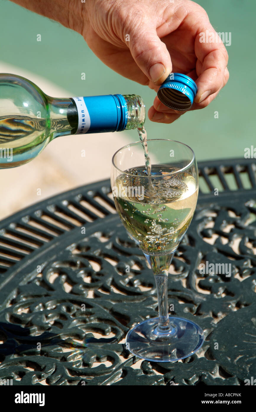 Screw cap on South African wine bottle White wine being poured into a wineglass Stock Photo