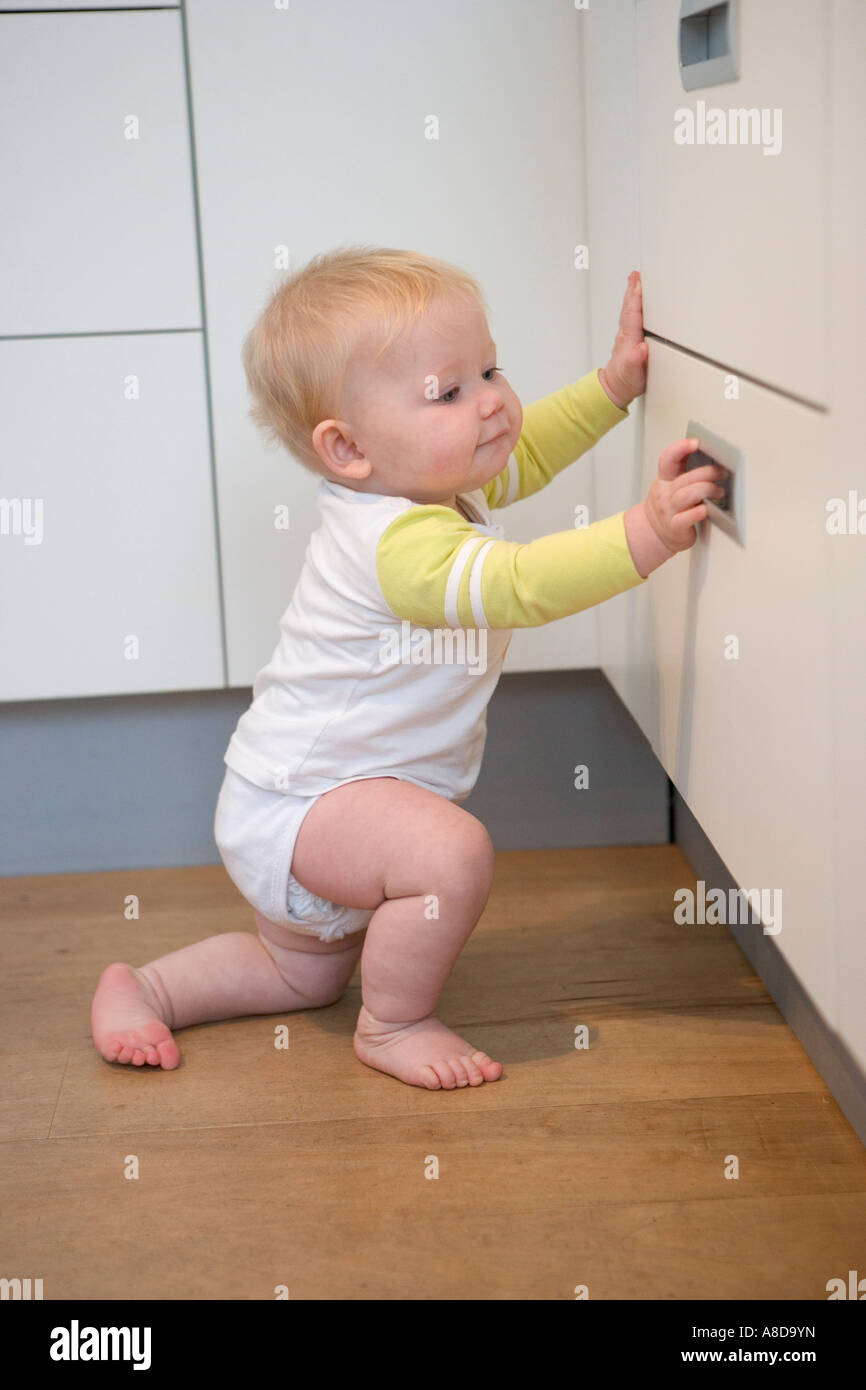 Baby discovering the kitchen cupboard Stock Photo Alamy