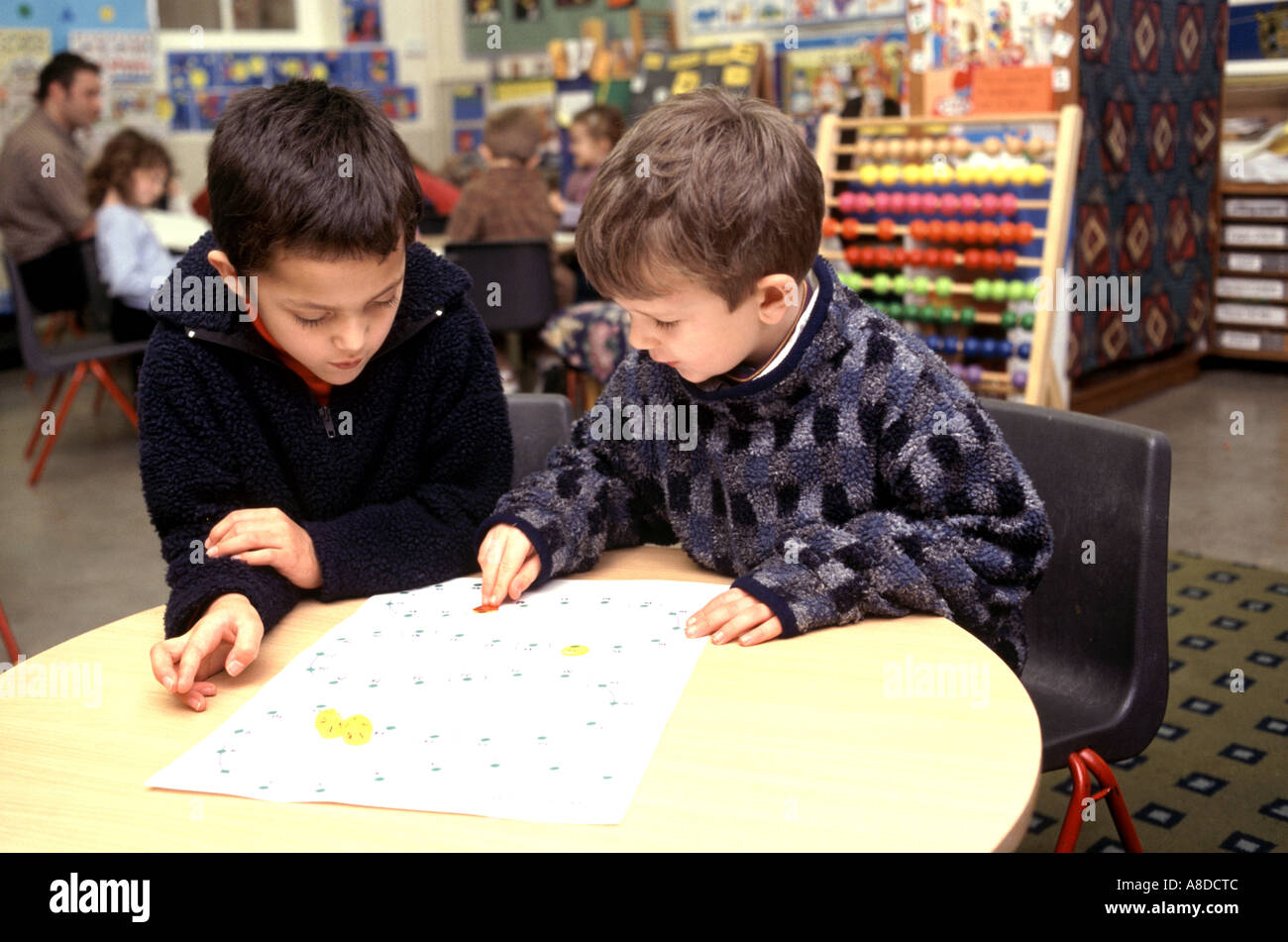 primary school boys playing snakes and ladders in classroom games Stock Photo