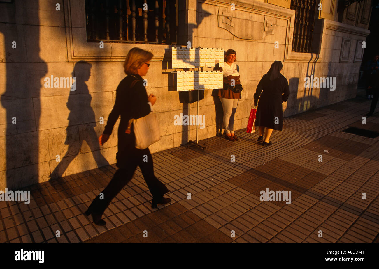 Lottery seller and pedestrians pass by in a street in Seville Andalucia Spain Stock Photo
