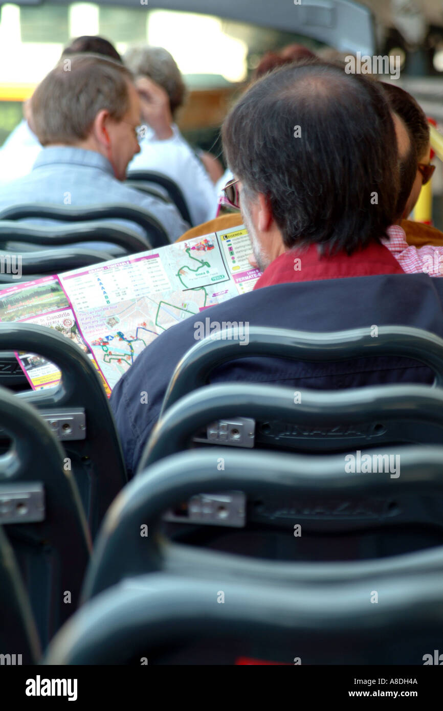 Tourist reading map on top deck of hop on siteseeing bus Florence